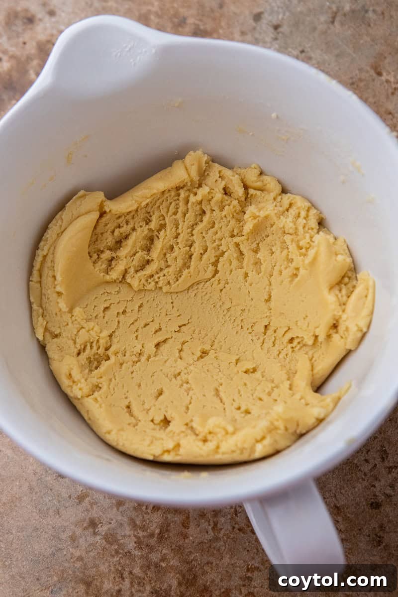 Crumbl's Divine Pumpkin Pie Cookies 5 Close-up of cookie dough being mixed in a bowl, showing the creamy texture.