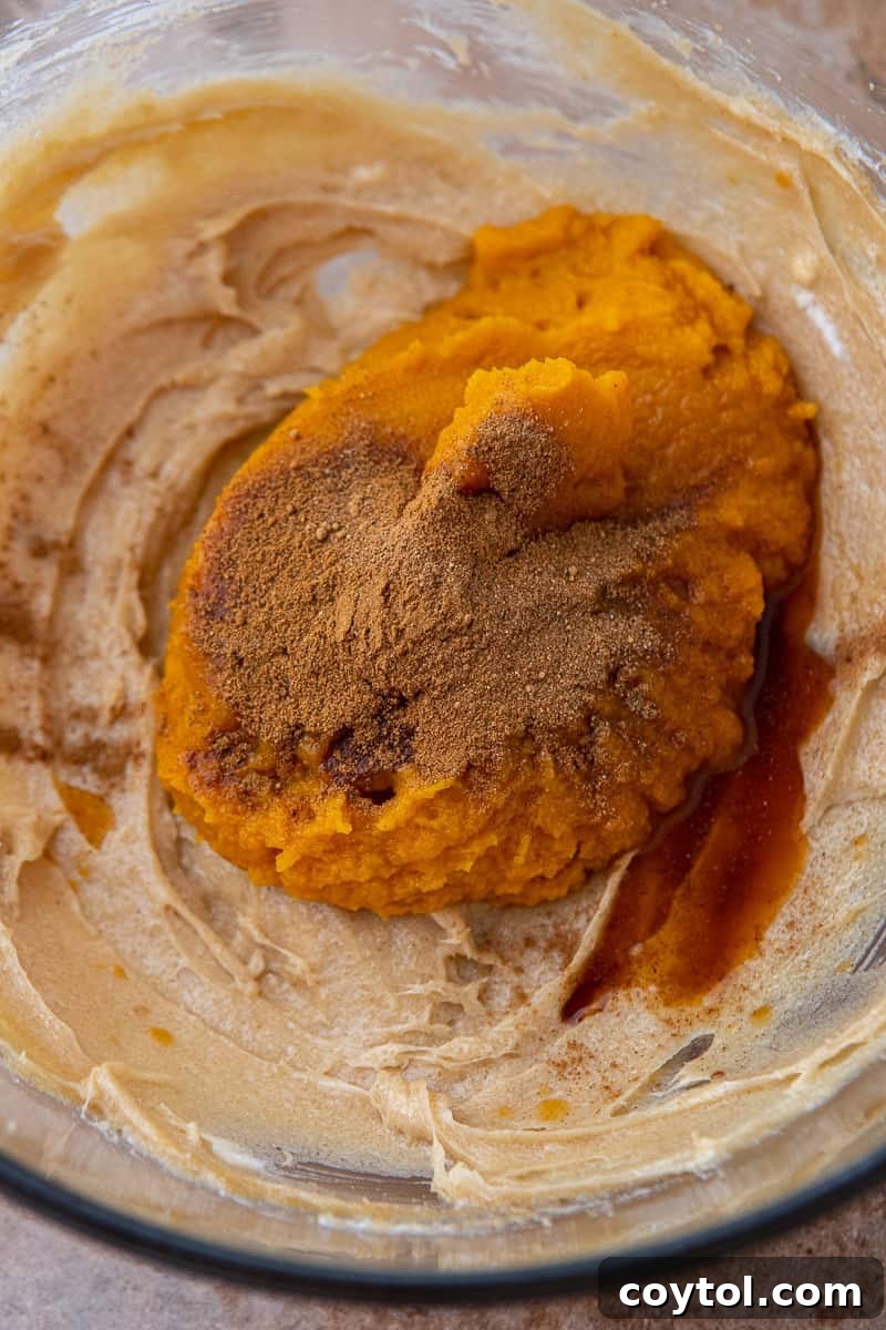 Crumbl's Divine Pumpkin Pie Cookies 7 Dry ingredients being added to the wet ingredients in a bowl.