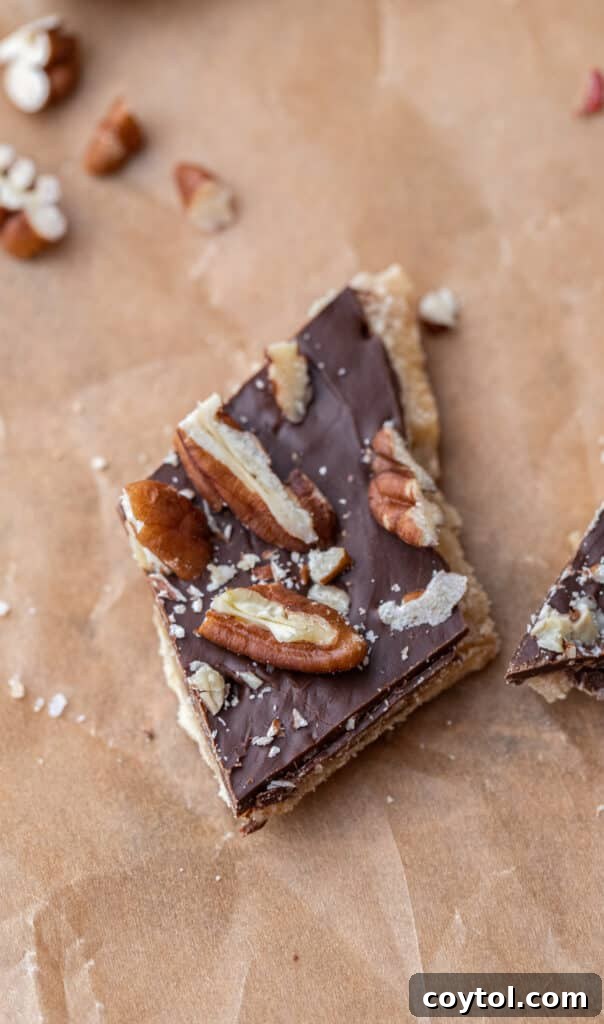 A perfectly sliced piece of Christmas Crack, showing the distinct layers of cracker, toffee, and chocolate with festive sprinkles.