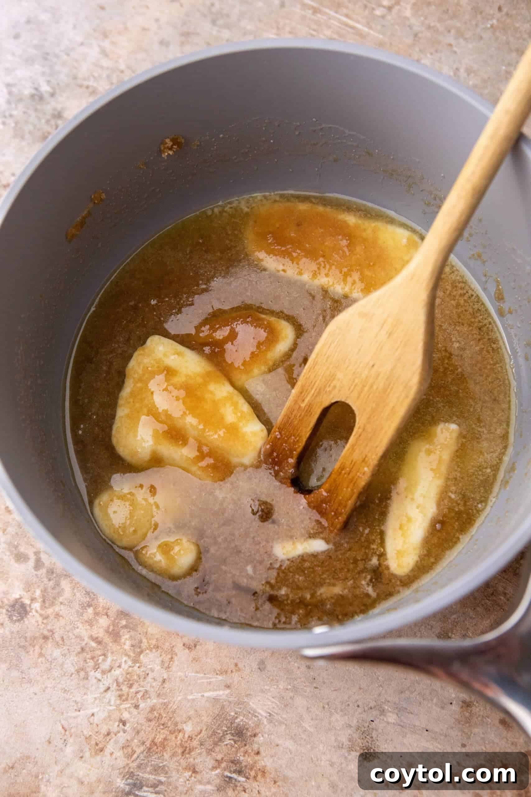 Butter and brown sugar melting together in a pot, beginning to form toffee.