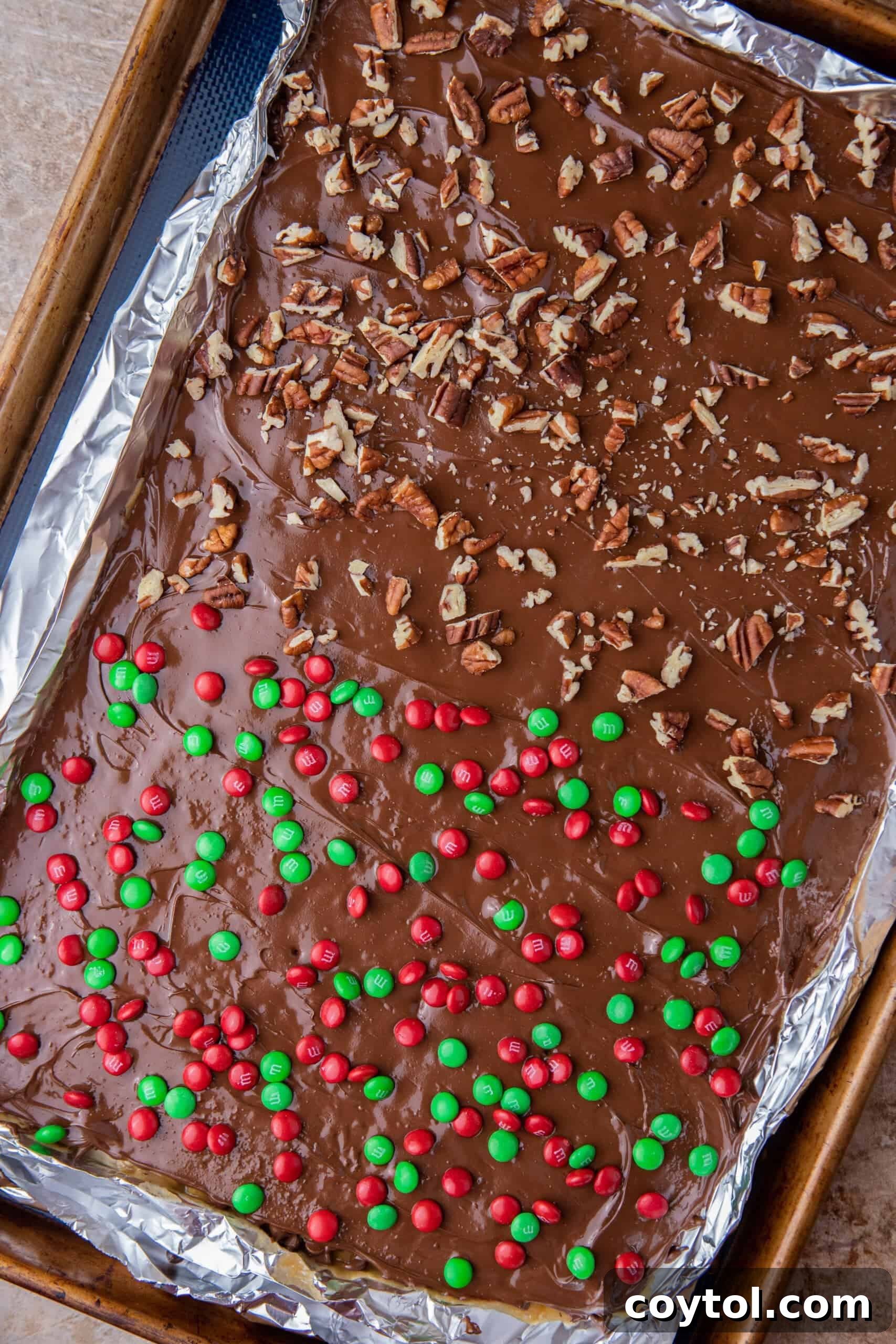 Finished Christmas Crack with pecans and M&Ms scattered on top, ready to set.