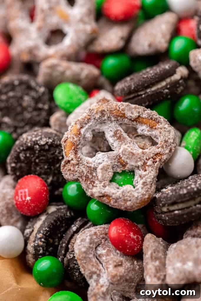 Powdered sugar coated pretzels and chocolate cookies in festive muddy buddies mix