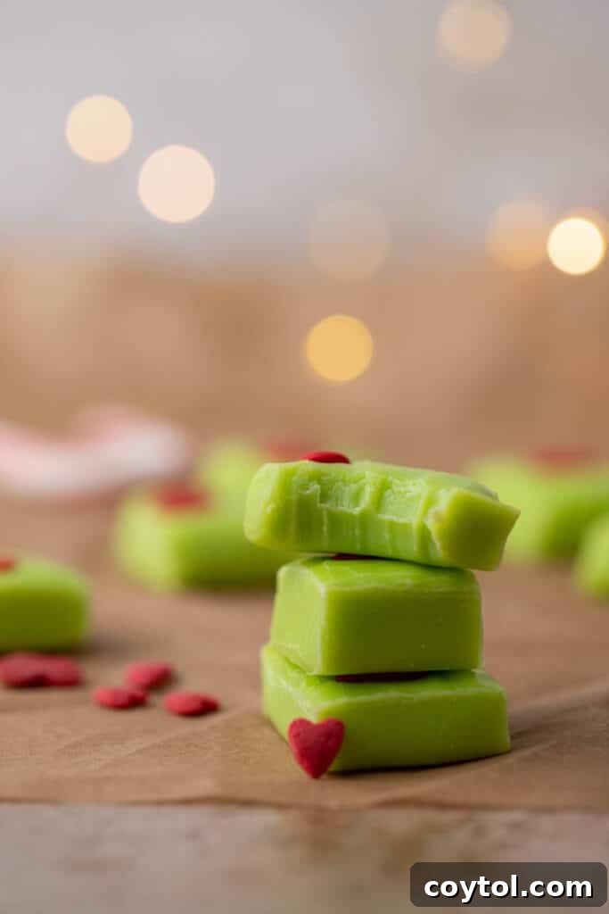 Stacked pieces of Grinch fudge with heart sprinkles