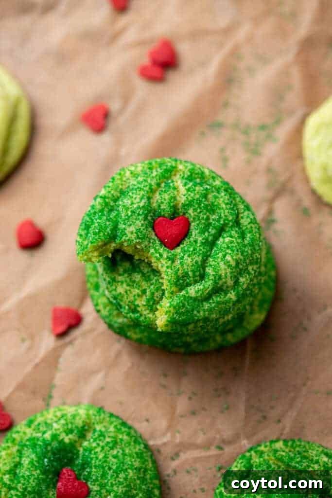 A Grinch sugar cookie with a bite taken out of it, revealing its soft, chewy interior.