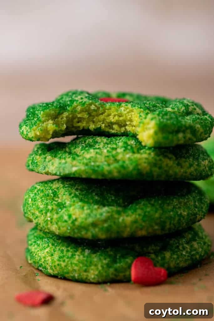 Close-up of freshly baked Grinch sugar cookies, still warm on a cooling rack, showcasing their soft texture and bright green color.