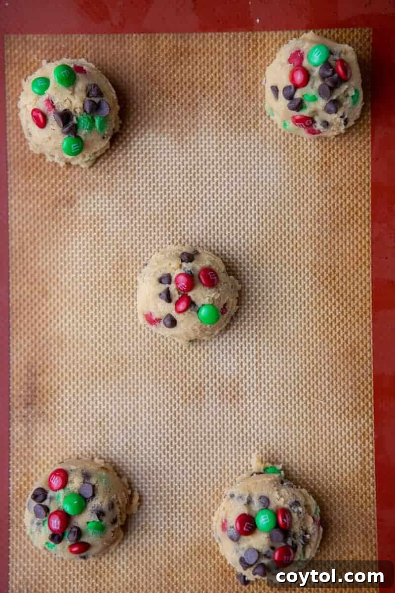 Sparkling Christmas M&Ms Chocolate Chip Cookies 8 Scooped cookie dough balls on a parchment-lined baking sheet before baking