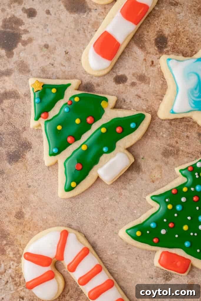 Christmas tree, candy cane, and star-shaped sugar cookies decorated with smooth icing.