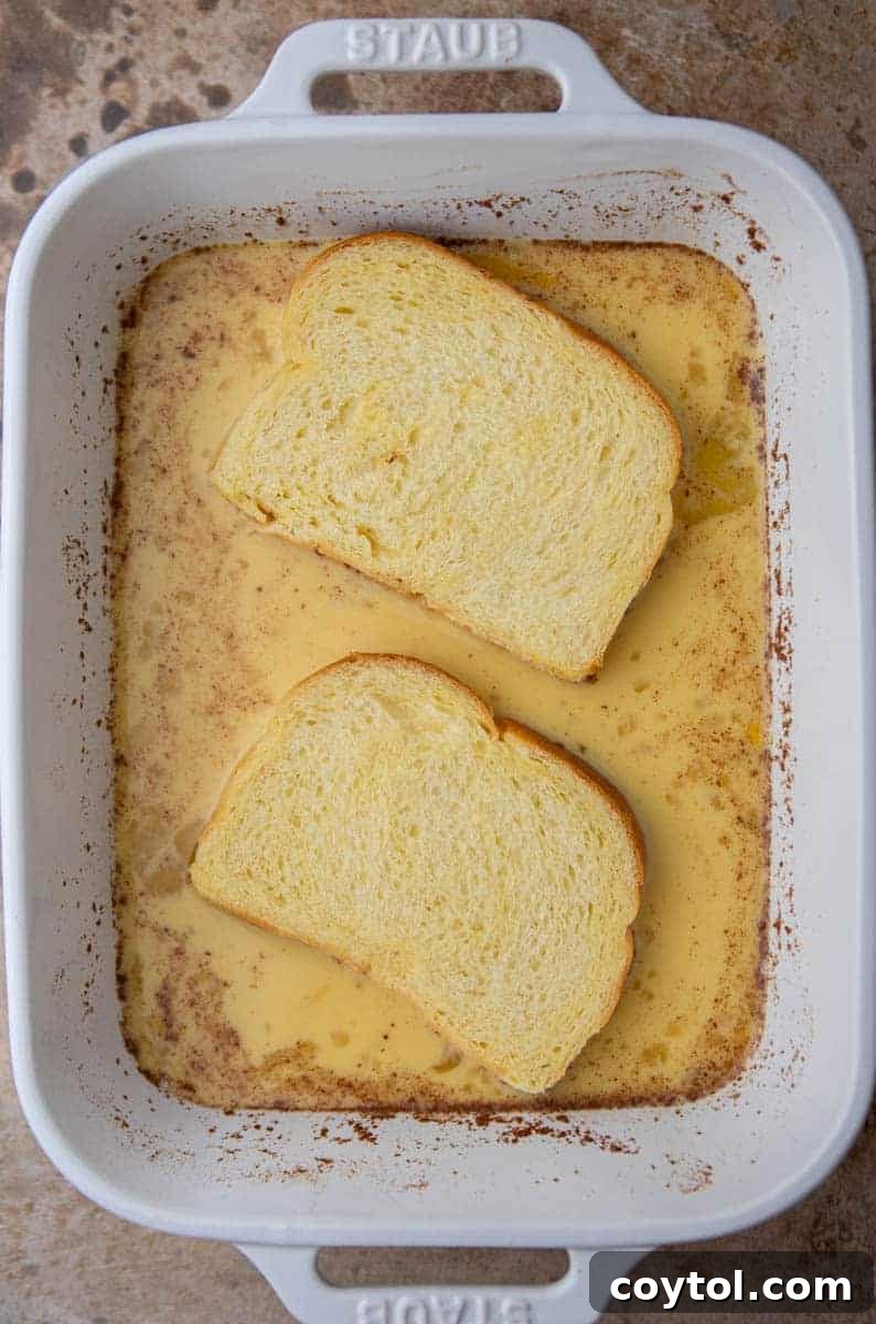 A slice of brioche bread soaking thoroughly in the rich egg custard mixture.