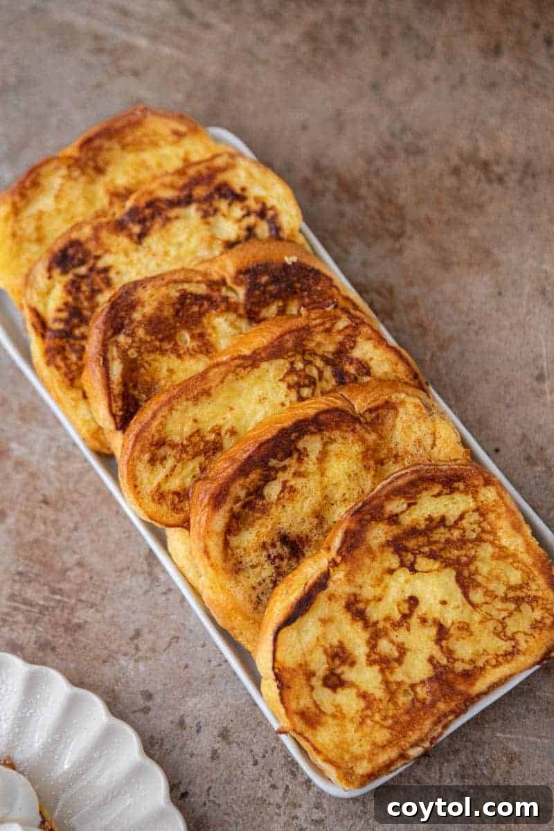 Two slices of golden-brown brioche french toast on a plate, garnished with berries.