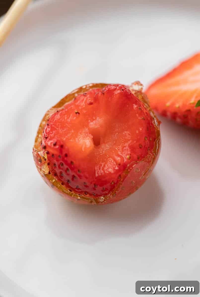 Candy coated strawberries with a bite taken out of them.