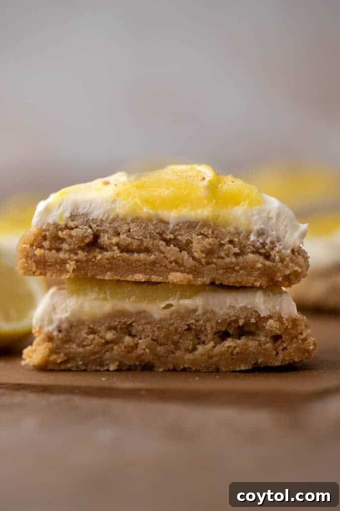 Divine Crumbl Lemon Cheesecake Cookies 2 Close up of a perfectly baked and frosted lemon cheesecake cookie, showing the layers of graham cracker base, cream cheese frosting, and lemon curd swirl.
