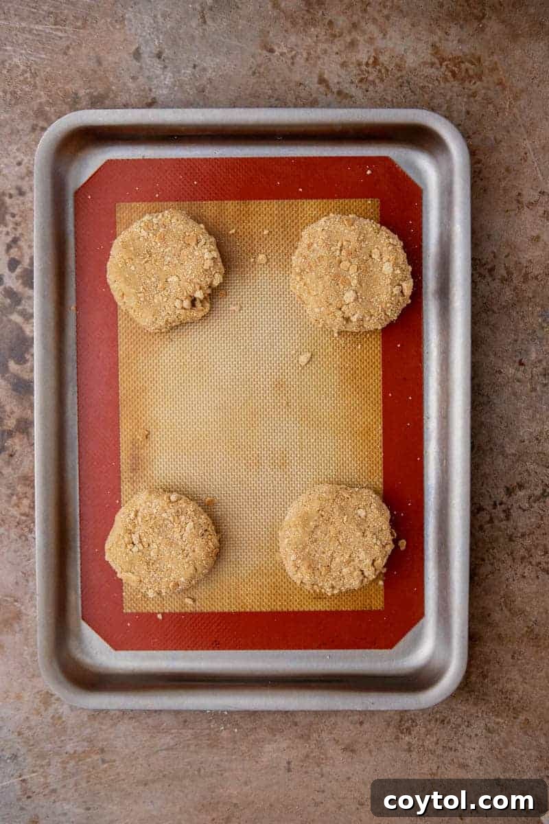 Divine Crumbl Lemon Cheesecake Cookies 8 Freshly baked graham cracker cookie bases, golden brown and cooling on a baking sheet.