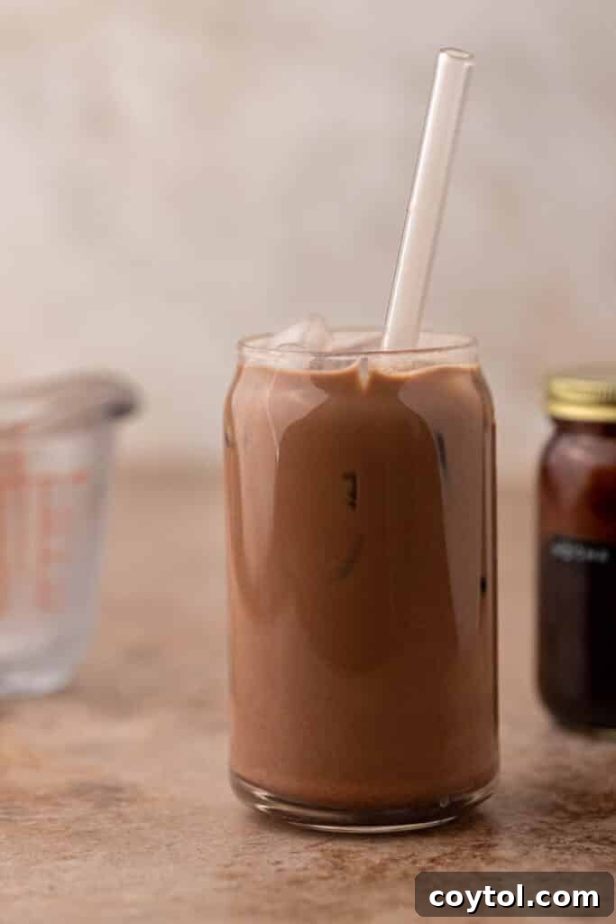 A glass of Chick-fil-A Mocha Creme Cold Brew with vanilla sweet cream swirling through the dark coffee and chocolate base, on a light background.