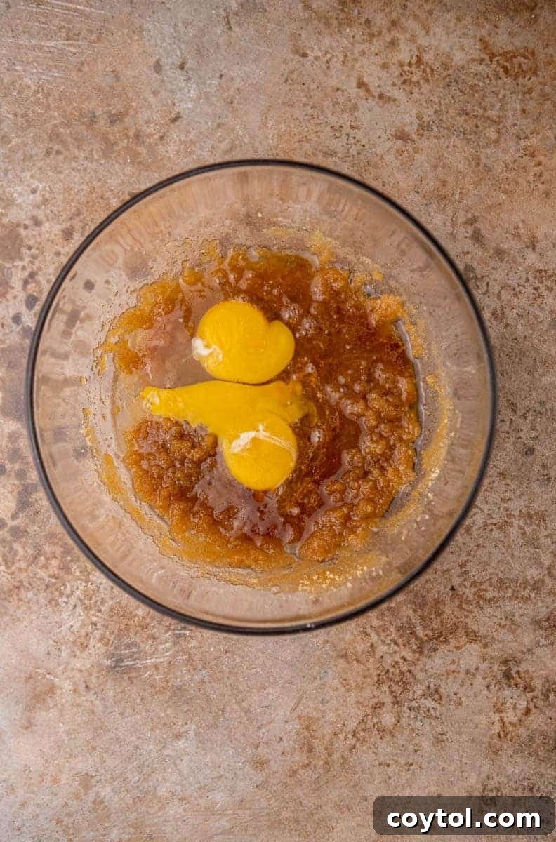 Sweet & Simple Valentine M&M Blondies 5 Wet ingredients (butter, brown sugar, eggs, vanilla) mixed in a bowl, showing a creamy texture.