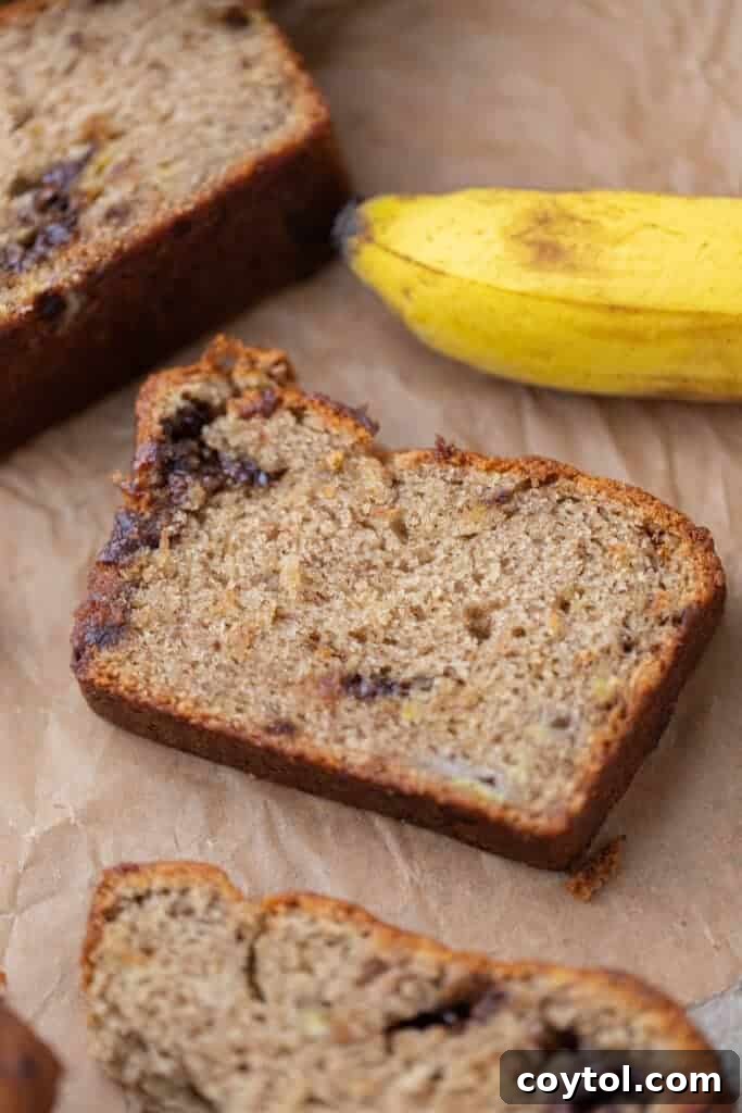 A perfectly sliced piece of moist eggless banana bread, showcasing its fluffy texture and golden-brown crust.