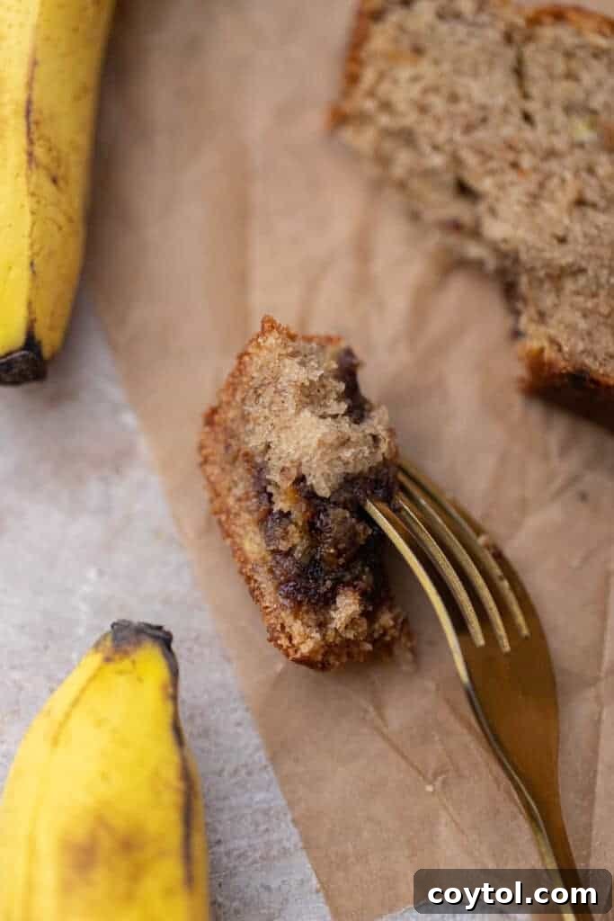 A close-up of a bite taken from a slice of eggless banana bread, revealing its tender, moist interior.