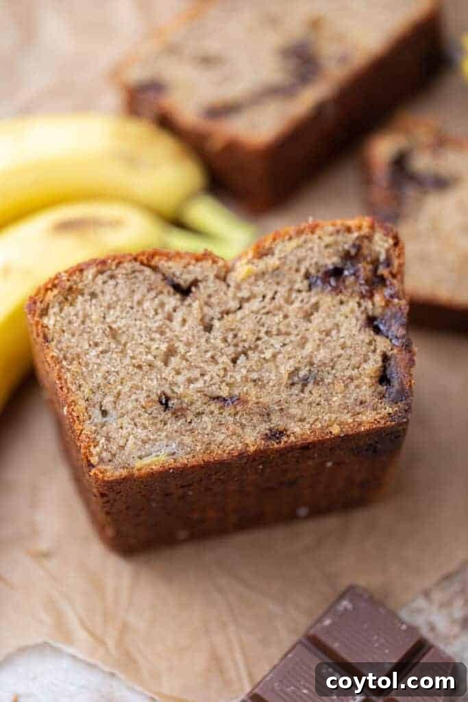 A half-eaten loaf of moist eggless banana bread, showing its inviting texture.