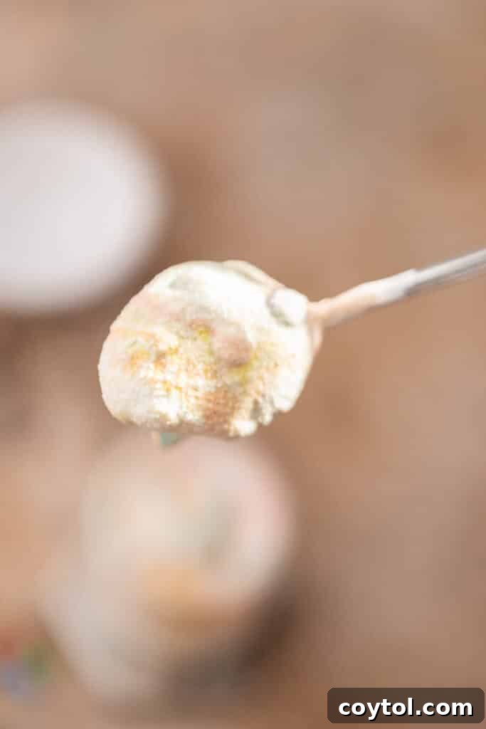 Spoonful of M&M's McFlurry showing the creamy ice cream and colorful candies.