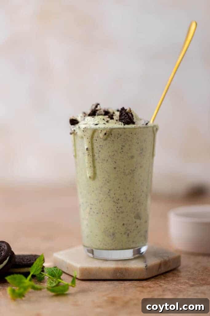 A vibrant green Shamrock Oreo McFlurry topped with crushed Oreos, with a spoon inserted.