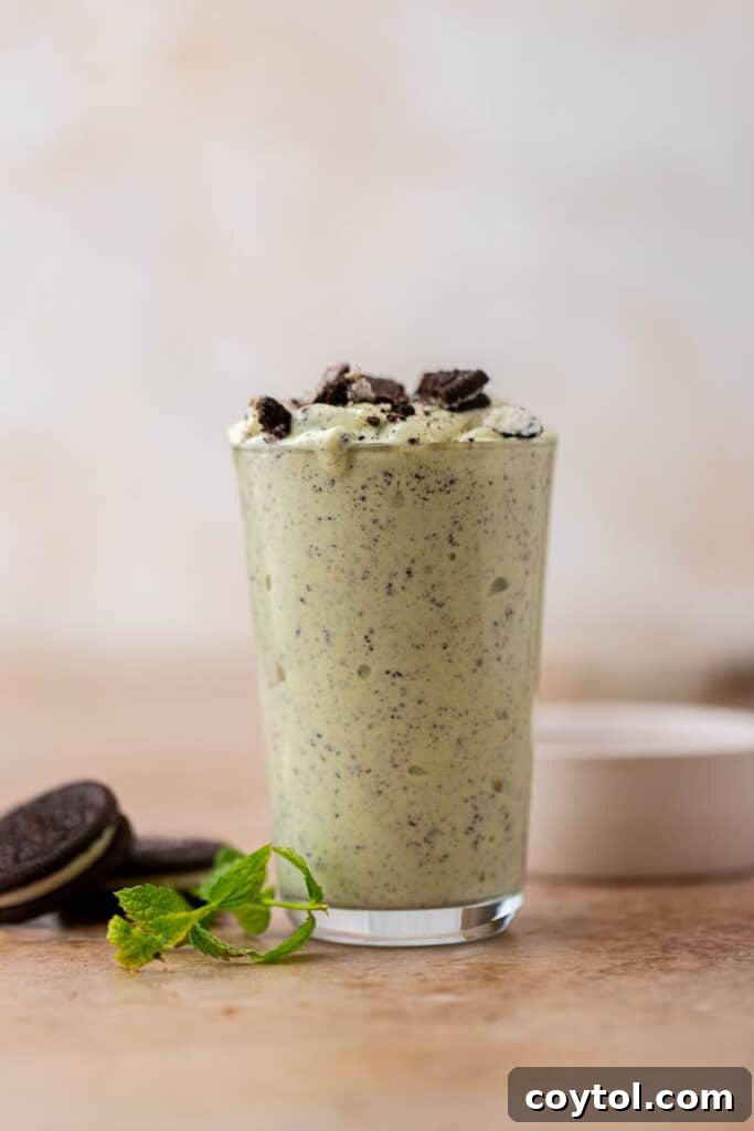 Close-up shot of a Shamrock Oreo McFlurry in a clear glass with a spoon.