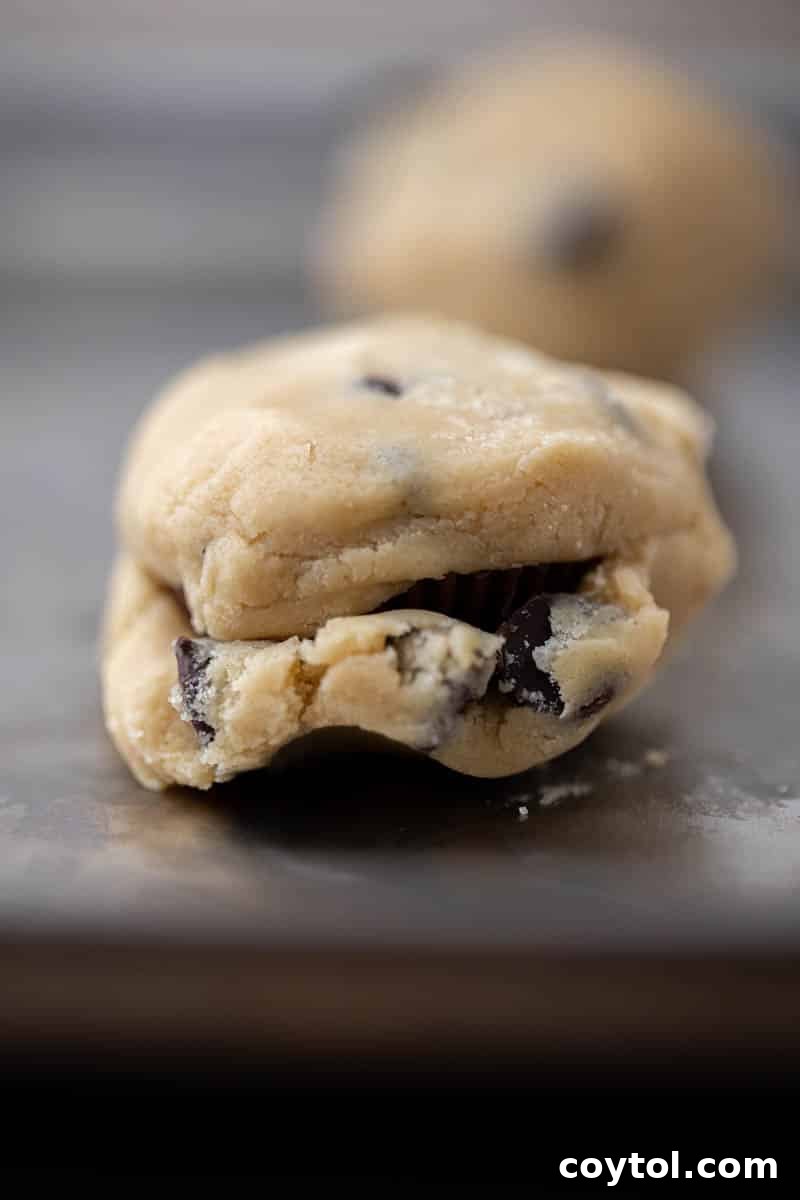 Simple Reese's Peanut Butter Explosion Chocolate Chip Cookies 9 Reese's stuffed chocolate chip cookies baking in the oven, starting to turn golden.