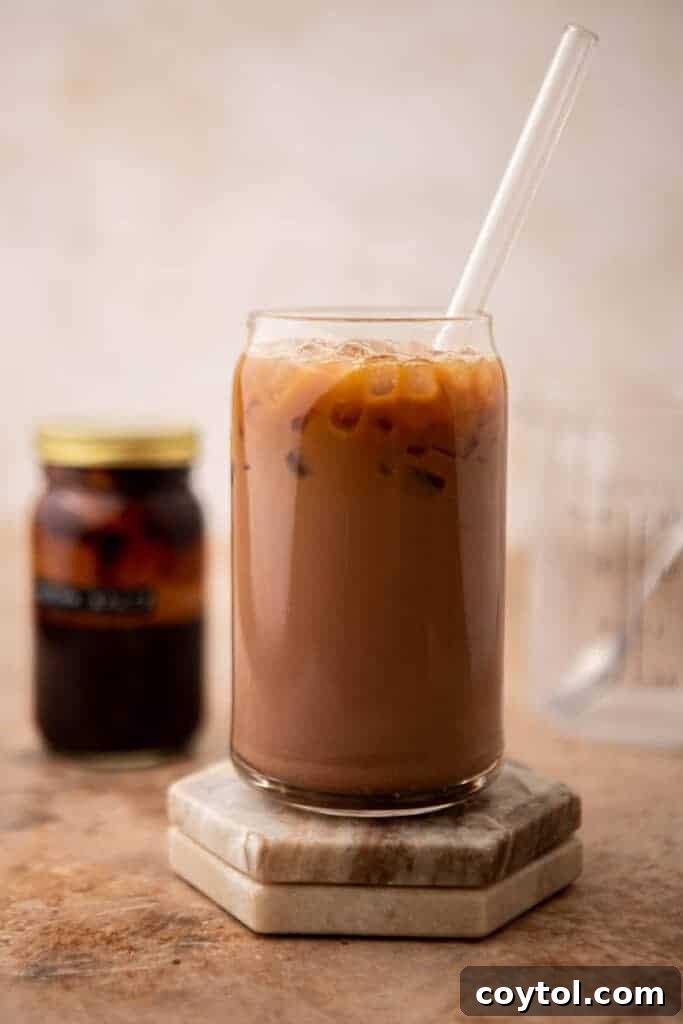 A freshly prepared iced mocha latte in a clear glass, showing distinct layers of chocolate, milk, and coffee, topped with whipped cream and chocolate drizzle, ready to be enjoyed.