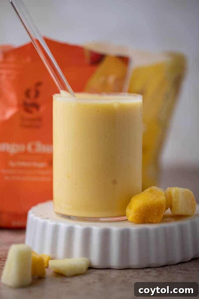 Mcdonalds pineapple mango smoothie in a tall glass, garnished with a slice of pineapple.