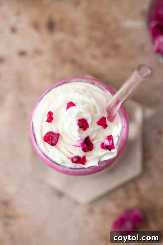 Overhead shot of a pink Barbie frappuccino in a tall glass with whipped cream