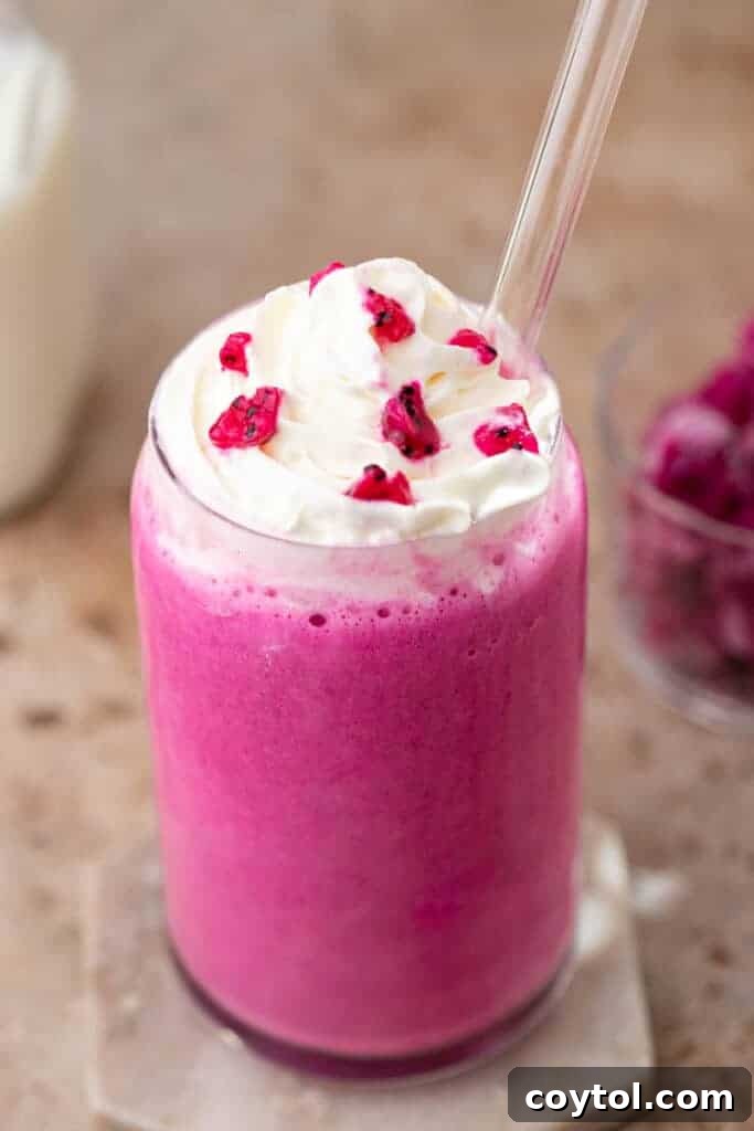 Pink frappuccino in a clear glass with whipped cream and sprinkles