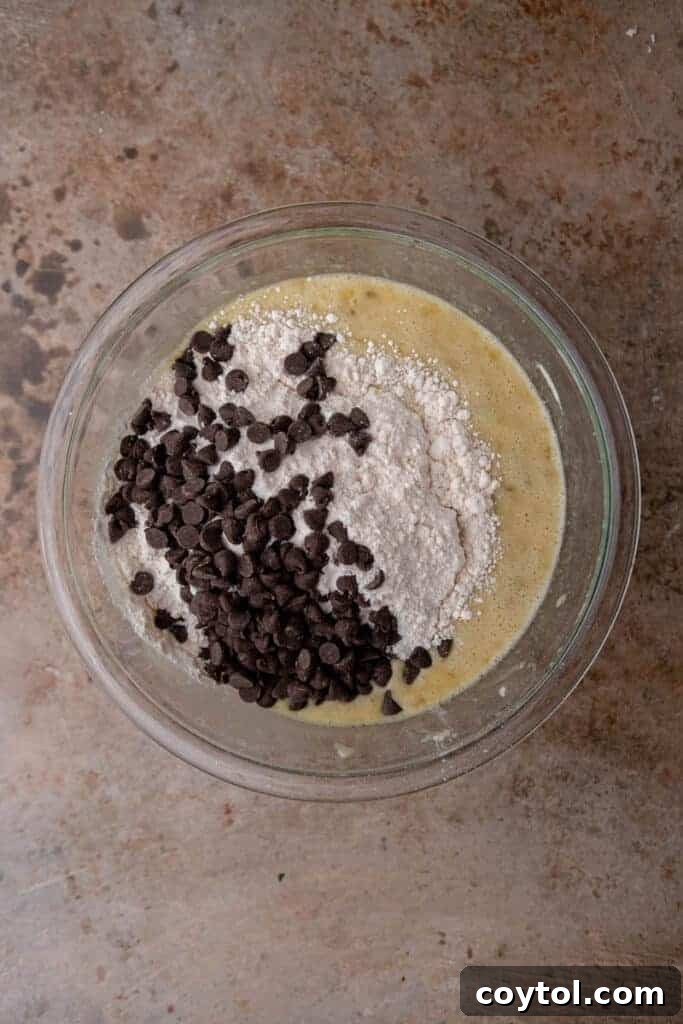 Wet ingredients for banana bread, including mashed bananas, eggs, and sour cream, blended in a bowl.