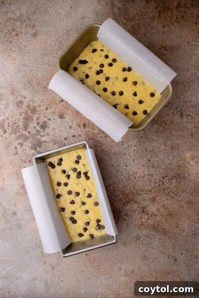 Cake mix banana bread batter, studded with chocolate chips, poured into a parchment-lined loaf pan.