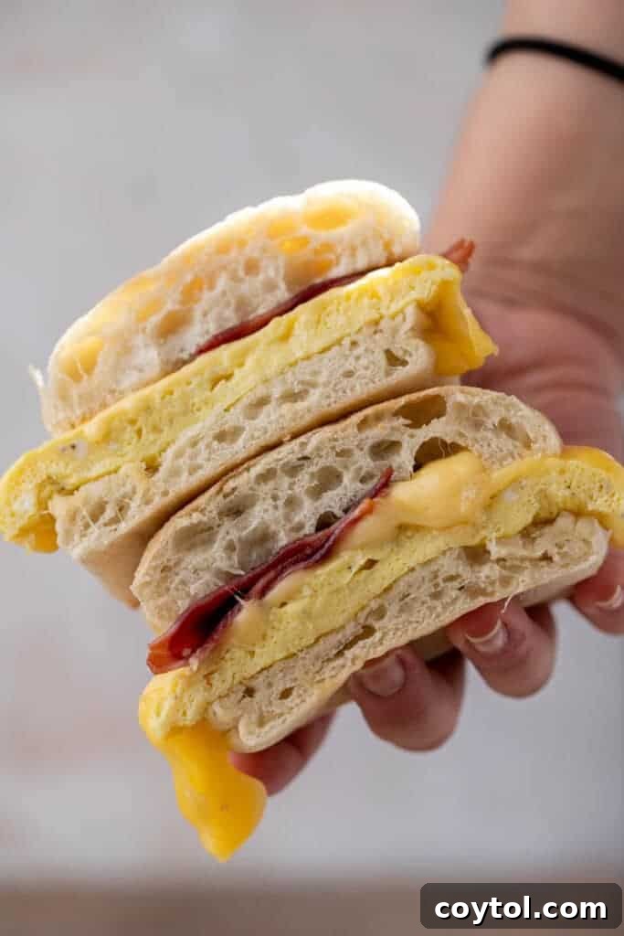Hand holding Starbucks bacon egg and cheese sandwich