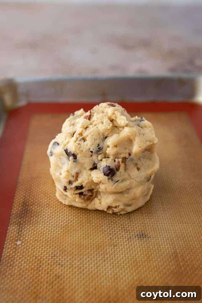 Large single cookie dough ball on a parchment paper-lined baking sheet