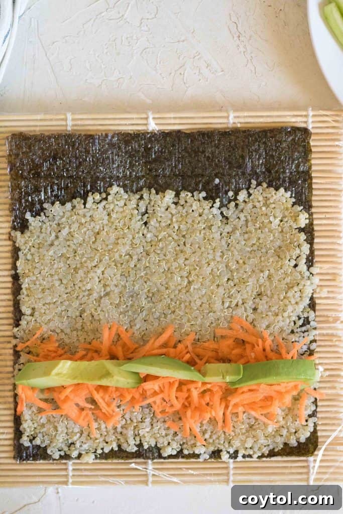 Crafting Vibrant Veggie Quinoa Sushi 12 Avocado slices being placed on top of other vegetables for sushi.