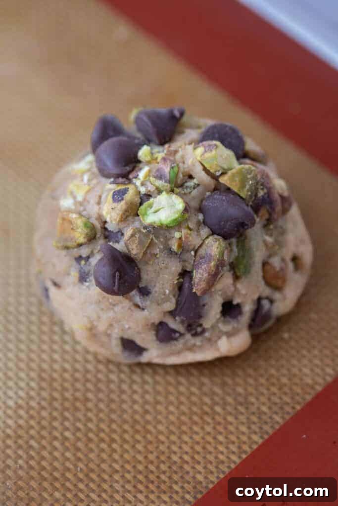 Decadent Brown Butter Pistachio Chocolate Chip Cookies 8 Scooped brown butter pistachio chocolate chip cookie dough balls placed on a baking sheet lined with parchment paper, ready for chilling or baking.