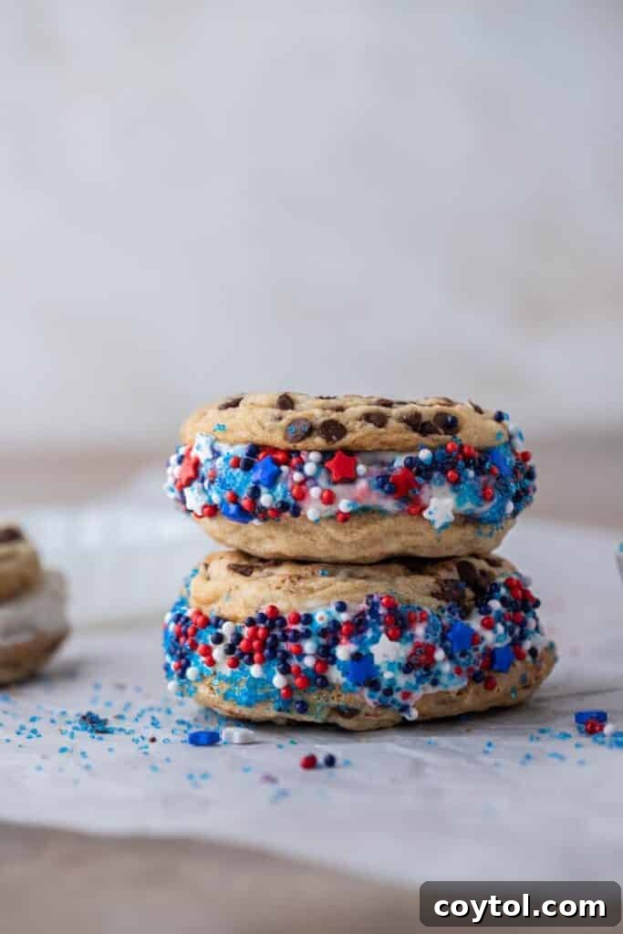 Patriotic ice cream cookie sandwich stacked, showing layers of cookie, ice cream, and sprinkles.