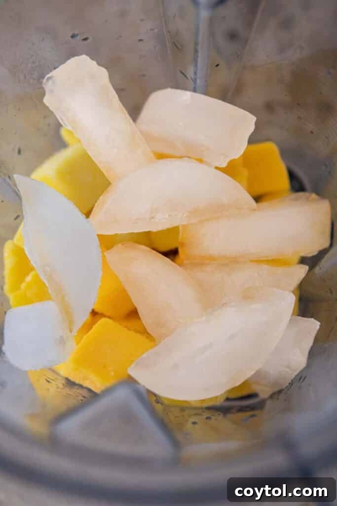 Frozen mango margarita ingredients being added to a blender.