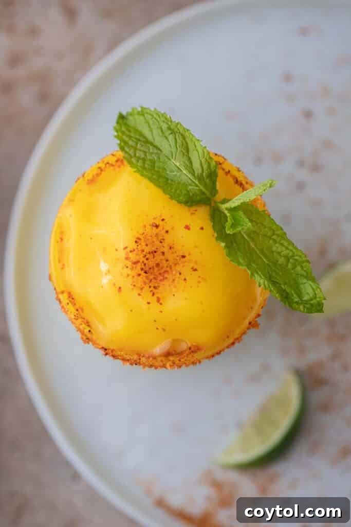 An overhead shot of two frozen mango margaritas, garnished with lime wedges.