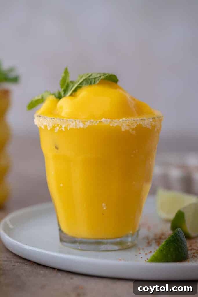 A close-up shot of a vibrant frozen mango margarita with a perfectly salted rim.