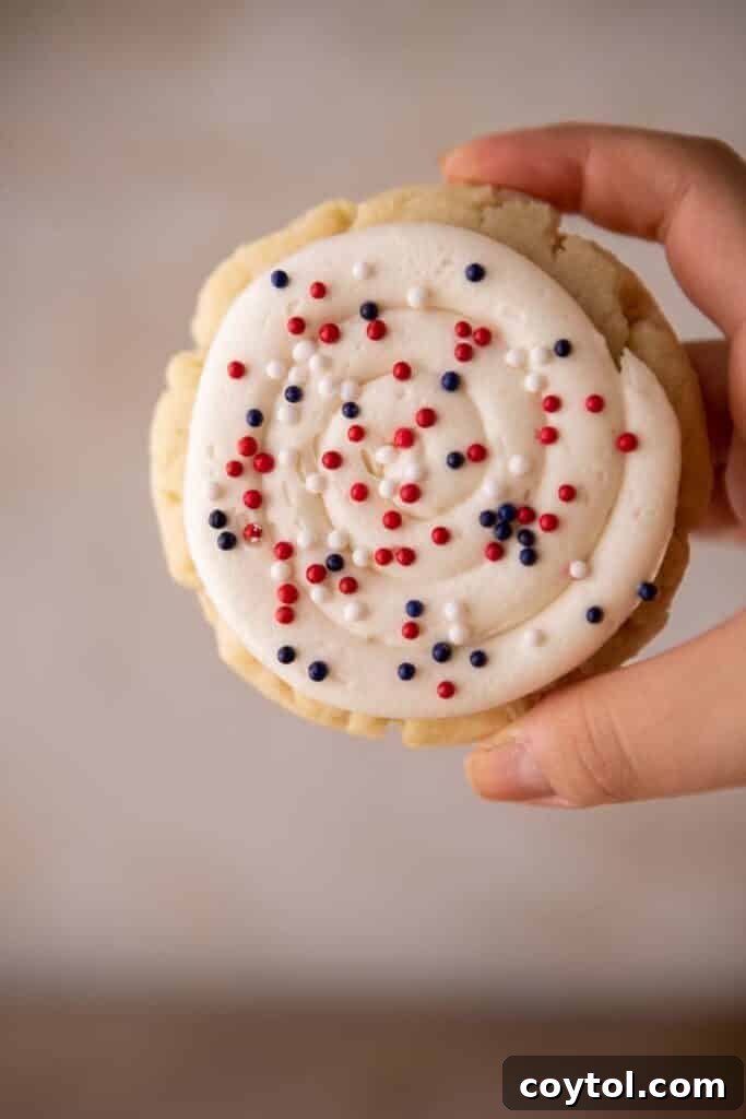 Crumbl All-American Birthday Cake Cookies 12 Hand holding a patriotic sugar cookie with festive sprinkles