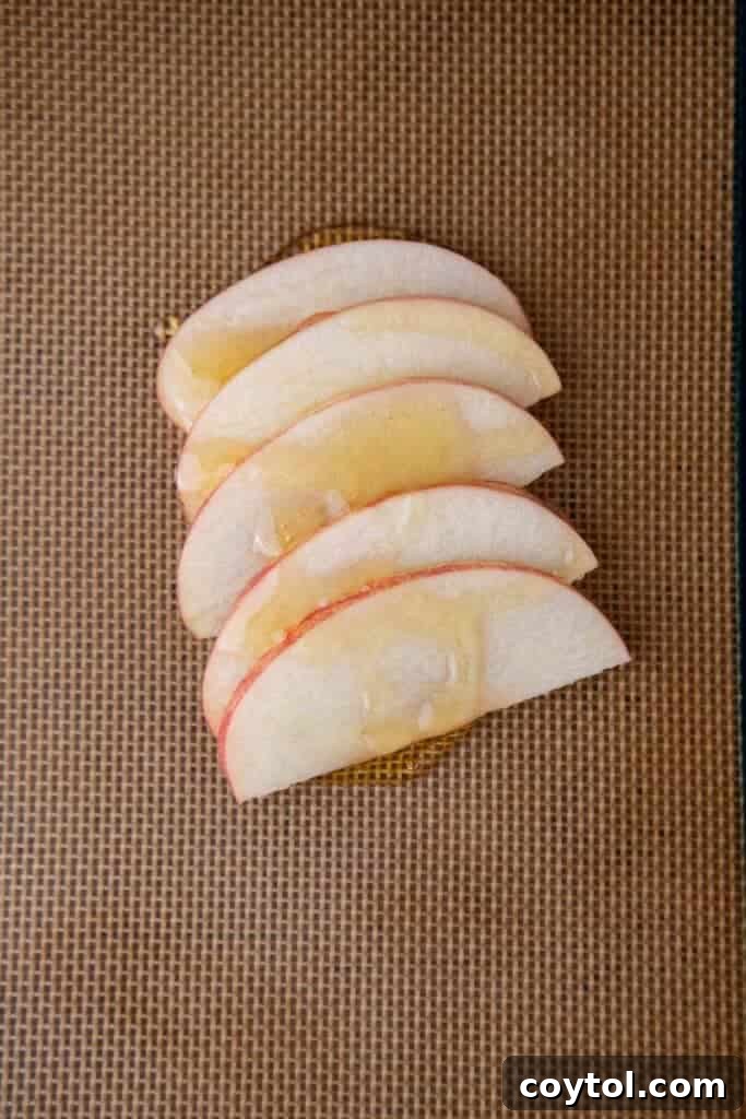 Flip for Flavor: Viral Upside-Down Pastries 6 Apple slices carefully placed on honey dollops on a parchment-lined baking sheet.