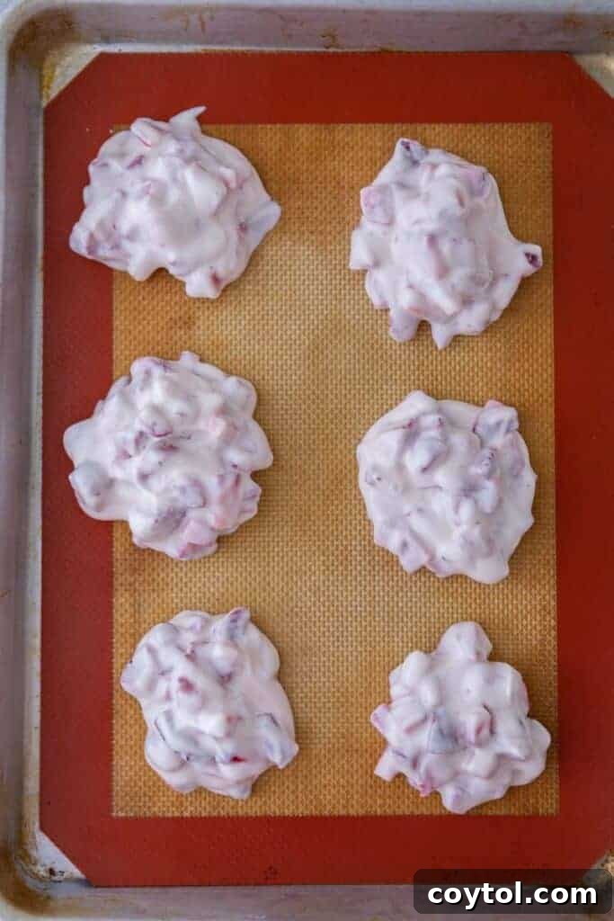 Decadent Chocolate Strawberry Yogurt Bites 7 Scooped strawberry yogurt clusters arranged on a parchment-lined baking sheet, ready for the freezer