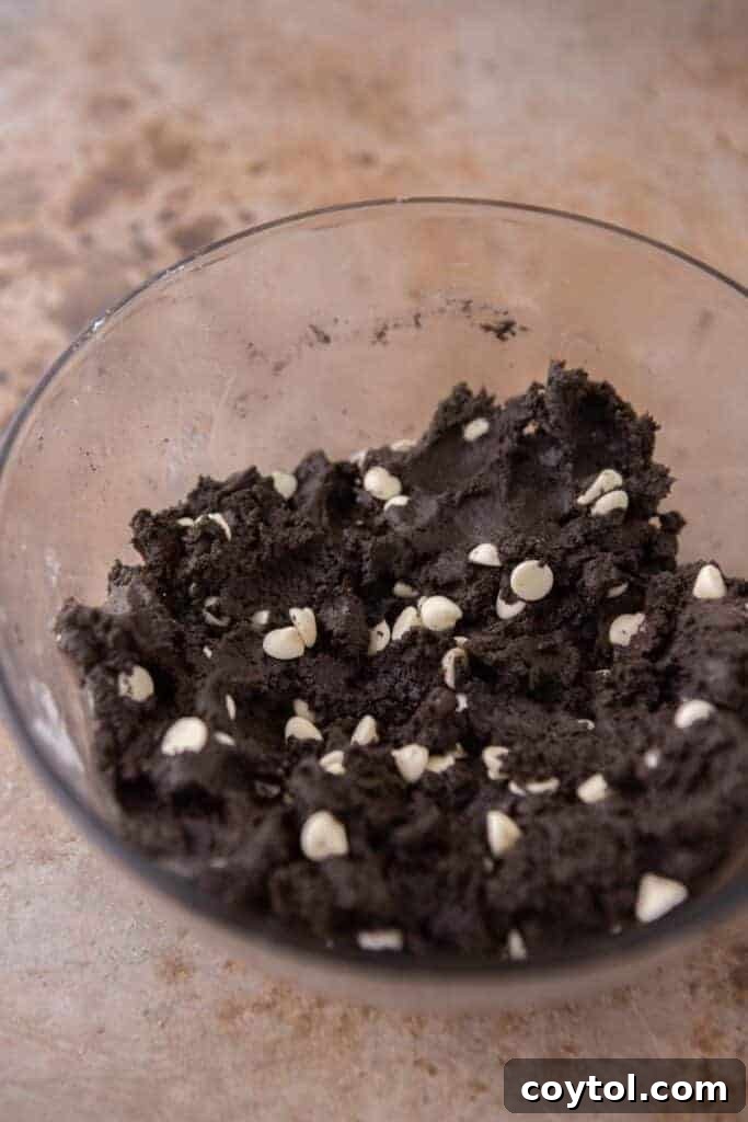 Crumbl Chocolate Cookie Cream Bliss 7 Finished cookie dough in a bowl with white chocolate chips and Oreo chunks