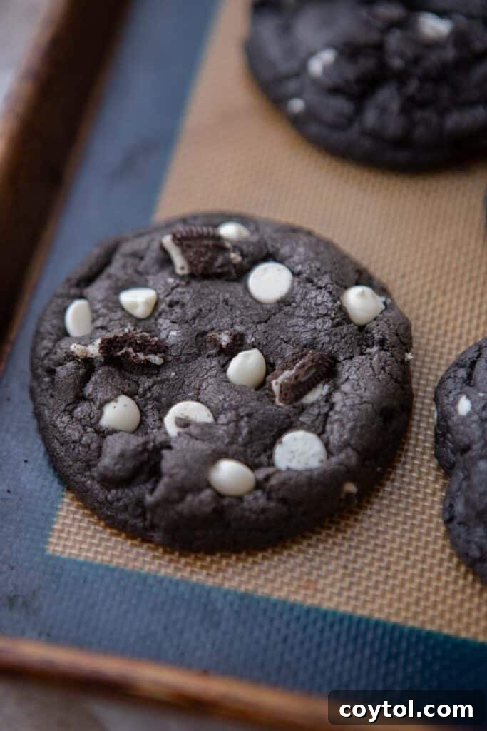 Crumbl Chocolate Cookie Cream Bliss 9 Freshly baked Crumbl chocolate cookies and cream cookies on a baking sheet