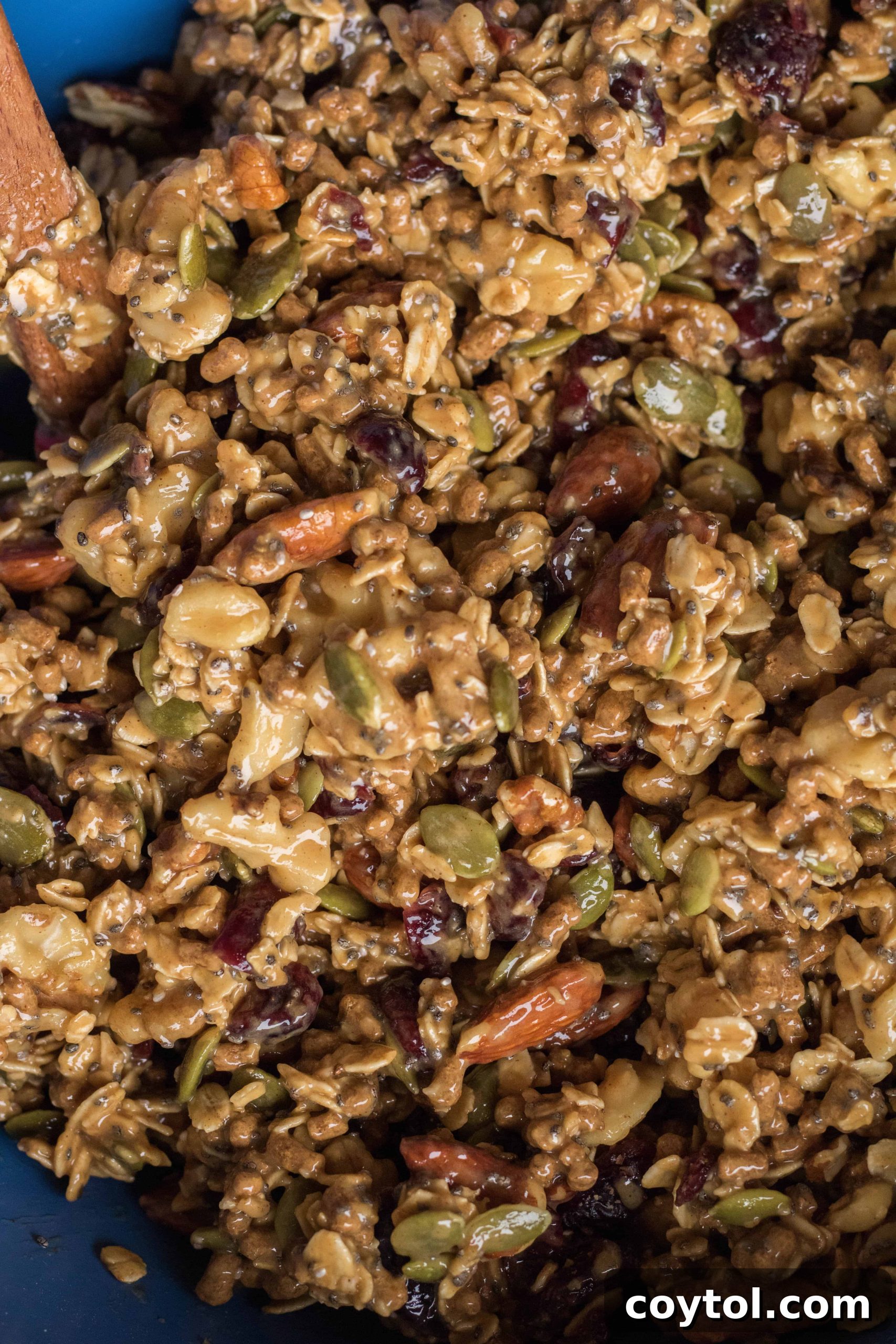 Pouring melted wet ingredients over the dry mix for trail mix energy bars.