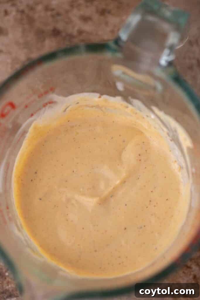 A cup filled with perfectly smooth and creamy blended cottage cheese, showcasing the desired texture for the queso base.