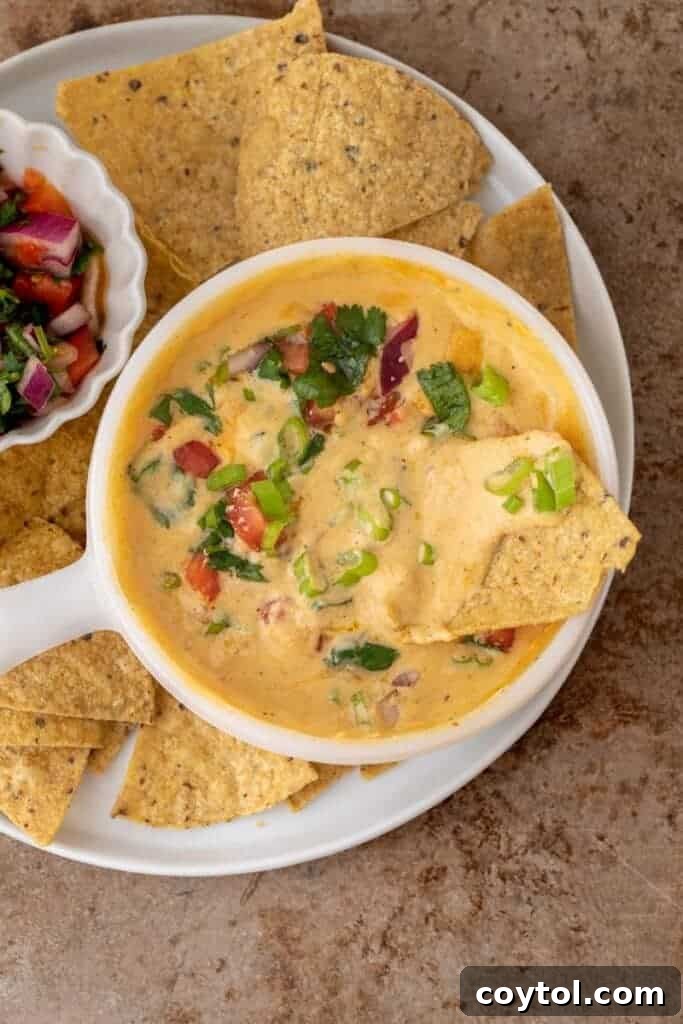 A full bowl of cottage cheese queso, presented invitingly on a wooden board with various dipping options around it.