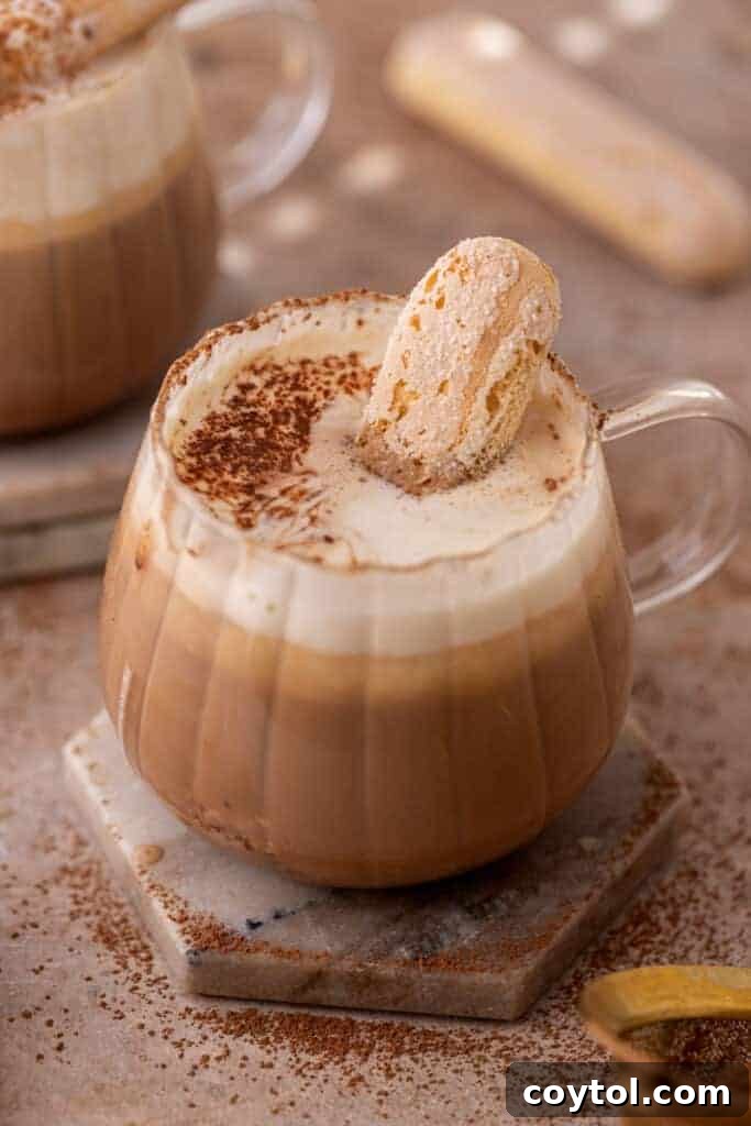 Creamy homemade tiramisu latte topped with mascarpone foam and cocoa powder, garnished with a ladyfinger.