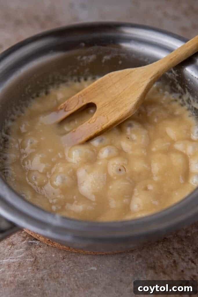 Caramel mixture boiling gently in a saucepan, showing the golden liquid stage of preparation.