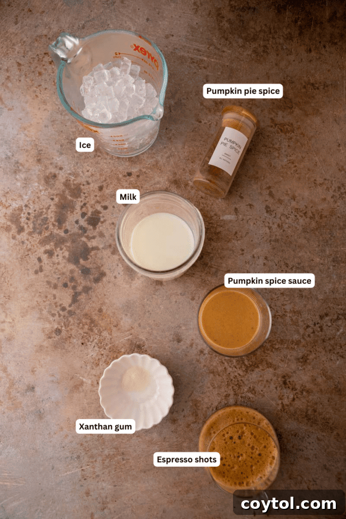 Various ingredients for a pumpkin spice frappuccino, including milk, coffee, pumpkin puree, and spices, laid out on a kitchen counter.